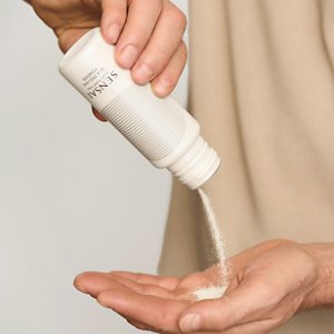Silky Purifying Silk Peeling Powder wird aus der Flasche in die Hand des Models geschüttet
